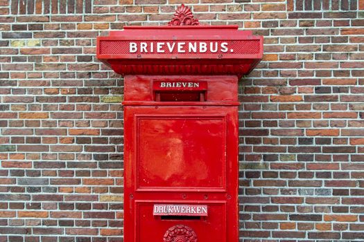 Oranje brievenbus Haarlem aan een drukke winkelstraat met fietsen en voorbijgangers
